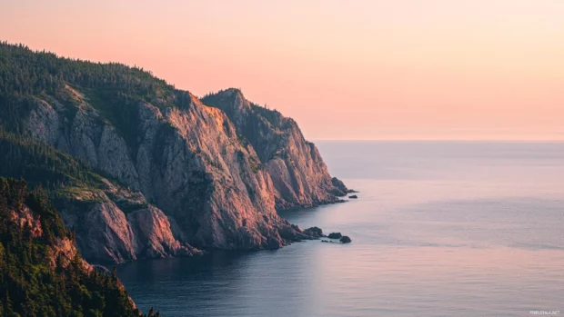 Morning light bathes the cliffs in soft peach hues at sunrise.