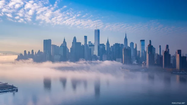Morning mist curls through skyscrapers in a quiet New York City skyline.