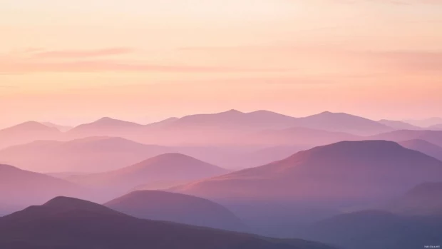 Mountains glowing pink and gold at sunrise.