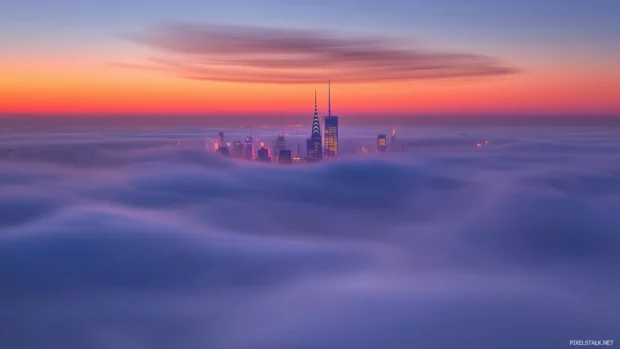 New York skyline in mist, tops of skyscrapers peek through foggy morning.