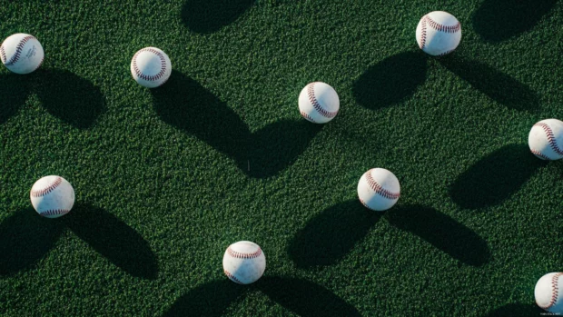Overhead view of multiple baseballs scattered across turf.