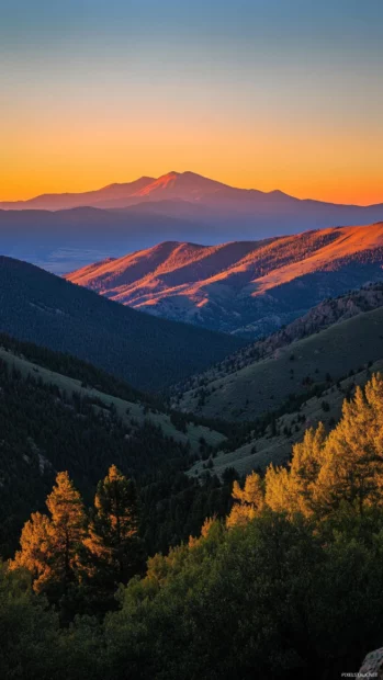 Peaks bathed in orange light awaken in a Mountain Sunrise wallpaper.