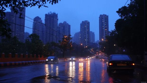 Rain slicked roads glisten under the lights of the night city.