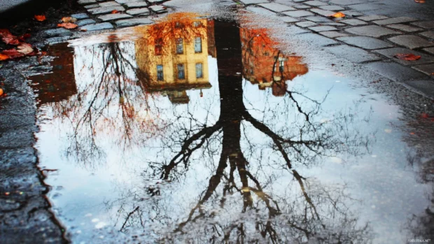 Reflections on city sidewalks after a rainfall, raining city wallpaper aesthetic.