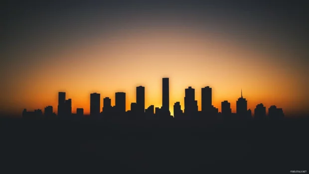 Silhouette of a modern city skyline at sunset, soft gradient sky.