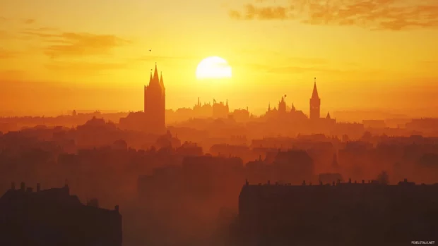 Silhouettes of towers appear as the sun rises behind the city.