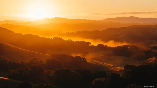 Sunrise Wallpaper for Desktop capturing golden rays over forested hills.
