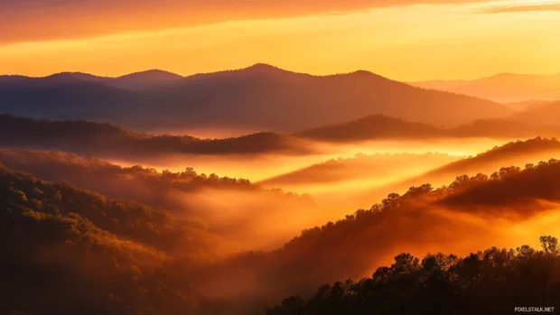 Sunrise Wallpaper for Macbook showing golden light cascading through misty mountains.