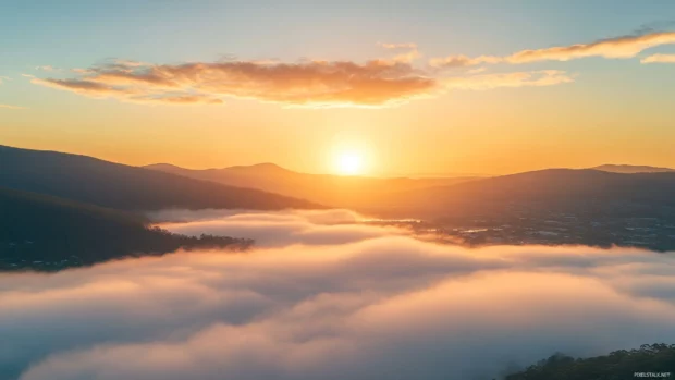 Sunrise breaking above riverbanks shrouded in fog.