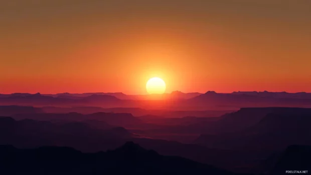 Sunrise glows behind distant mesas in this Sunrise Wallpaper in Desert.