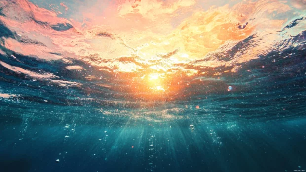 The ocean sparkles under a radiant sunrise.
