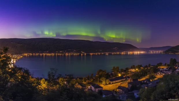 Vibrant night sky, Northern Lights in green, blue, purple over mountain range.