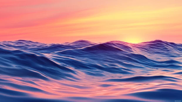 Waves gently rolling beneath a colorful sunrise sky.