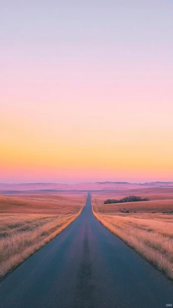 Wide open plains light up under a soft pink sunrise.