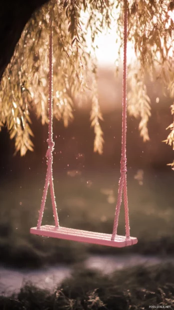 A Pink Girly swing hanging from a willow tree under soft light.