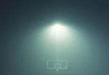 A basketball rests at the three point line as fog rolls across the court.