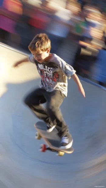 A boy skateboarding in a vibrant skatepark, with dynamic motion blur capturing his mid air trick.