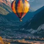 A colorful hot air balloon drifting over a scenic valley, with a radiant sunrise creating a golden glow.