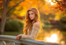 A girl with long, wavy hair standing on a bridge during golden hour, soft cinematic lighting.