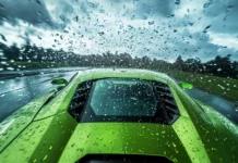 A green Lamborghini powers through raindrops that streak across the windshield with dramatic sky.