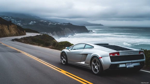 A silver Lamborghini racing along a cliffside highway with ocean spray in the distance.