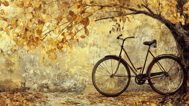 A vintage bicycle leaning on a tree with golden leaves, found in many fall themed wallpapers.