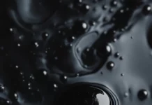 Abstract black ink drops floating in dark water.