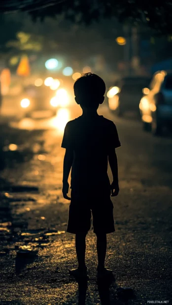 As headlights blur past, the boys silhouette remains still and composed.