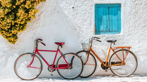 Brightly colored bicycles leaning against a whitewashed wall, hinting at lazy summer explorations.