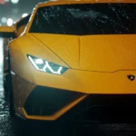 Close up of Lamborghini headlights reflecting ambient city glow in the rain.