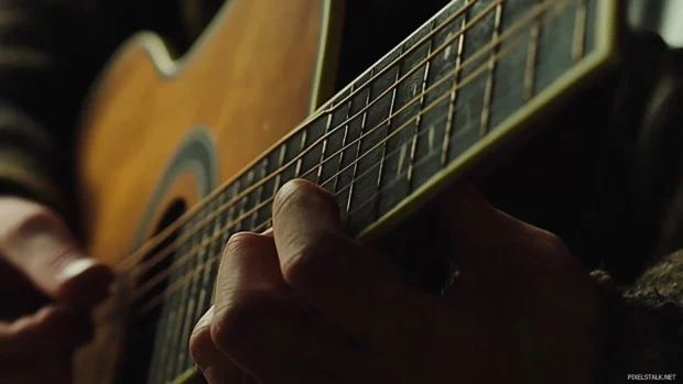 Close up of fingerpicking on a country acoustic guitar.