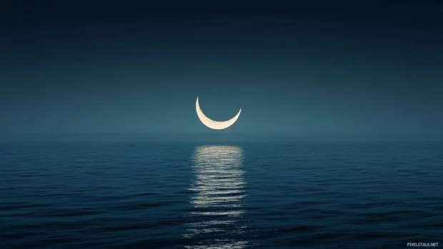 Crescent moon reflecting over a calm, black sea.