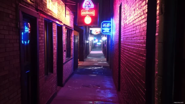 Deep alley with only one flickering neon sign.