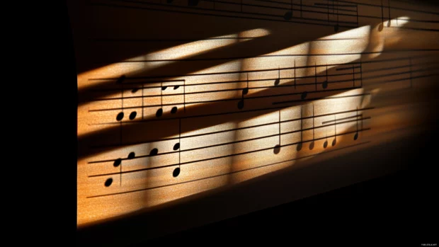 Detailed music notes on musical staff under sunlight with soft window shadows.