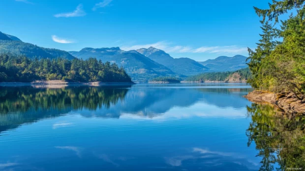Free download Windows 10 lock screen wallpaper 4K featuring a serene lake reflecting surrounding mountains.