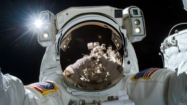 Light from a supernova reflects off the astronauts visor as they drift alone.