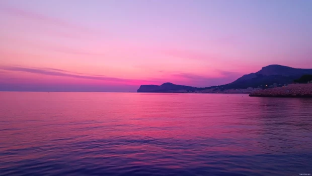 Pale pink skies fading into deep purples as the sun dips below the summer sea.
