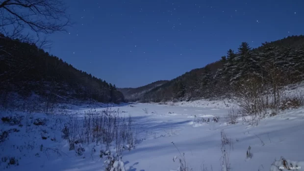 Pretty snow covered valley under starlit sky.
