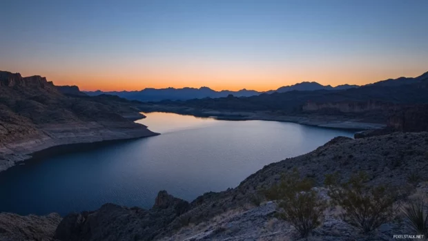 Shadows falling across a pretty mountain lake under twilight sky.