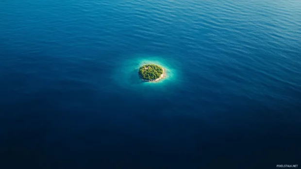 Tiny island floating in endless Pretty Ocean blue.