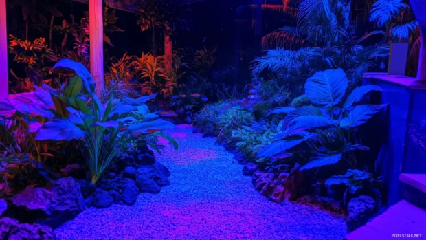 With soft blue lighting illuminating a detailed gravel bed, a vibrant fish tank is filled with colorful tropical fish and lush green plants.