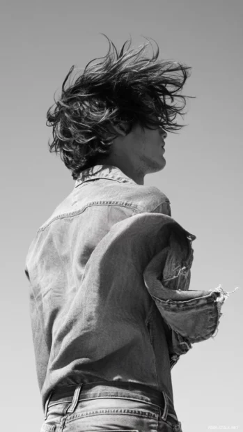 With windblown hair and faded denim, the boy surveys the skyline.