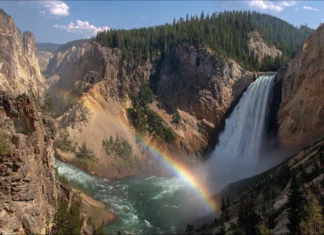 4k waterfall rainbow wallpaper capturing crystal clear water plunging into deep canyon pool with brilliant full rainbow across the mist.