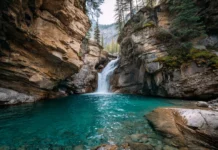 4k waterfall wallpaper showcasing a wide curtain of water spilling from rocky cliff into turquoise basin.