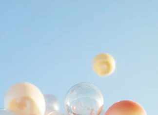A charming birthday iPhone wallpaper featuring a group of balloons in various shapes and colors against a clear sky.