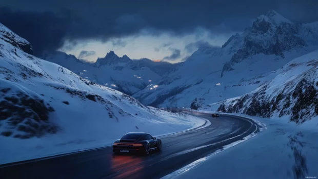 A high speed Porsche shot captured on a mountain pass with snow capped peaks glowing in the background.