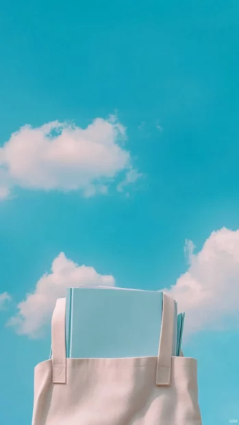 Aesthetic book peeking from a tote bag with gentle color tones and sky above.