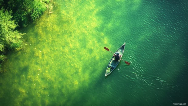 Bass fishing from kayak wallpaper showing a peaceful solo fisherman drifting on still green waters.