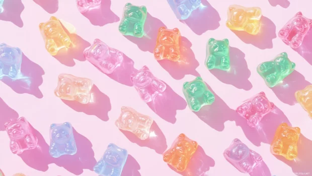 Cute gummy bear wallpaper showcasing multiple colorful gummy bears scattered on a pastel pink backdrop.