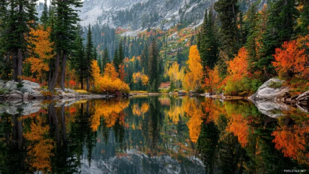 Fall forest reflected perfectly in a mountain lake, surrounded by trees bursting with seasonal colors.